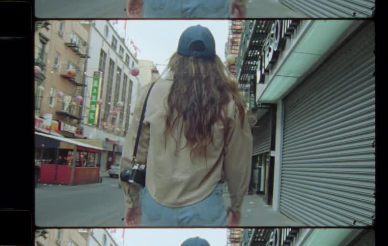 Back of a woman walking on the sidewalk of a small street