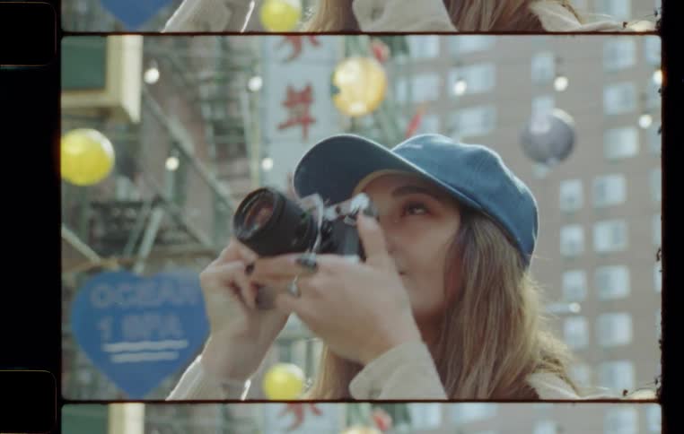 A blonde girl in a blue cap is taking pictures and looking around