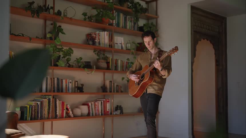 Male musician playing the guitar indoors during day time
