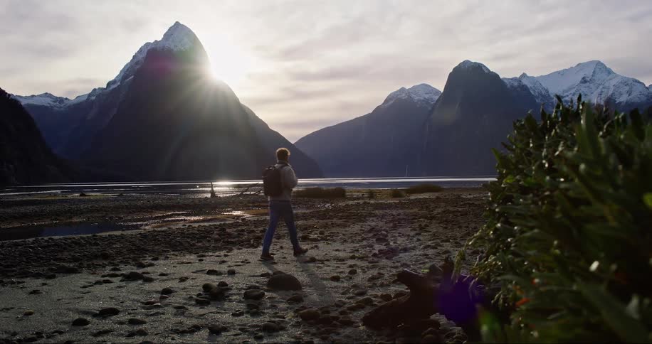 Man walking alone near a river at sunset