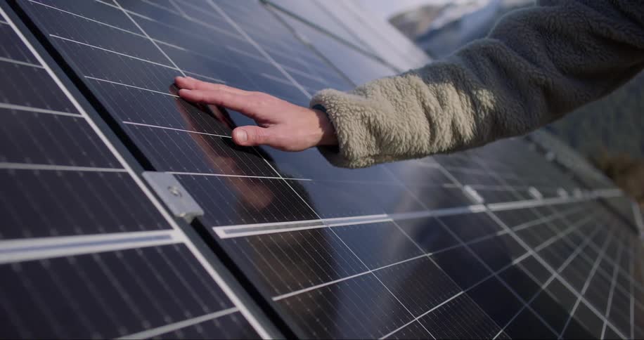 Close up of a person running their hand over a solar panel