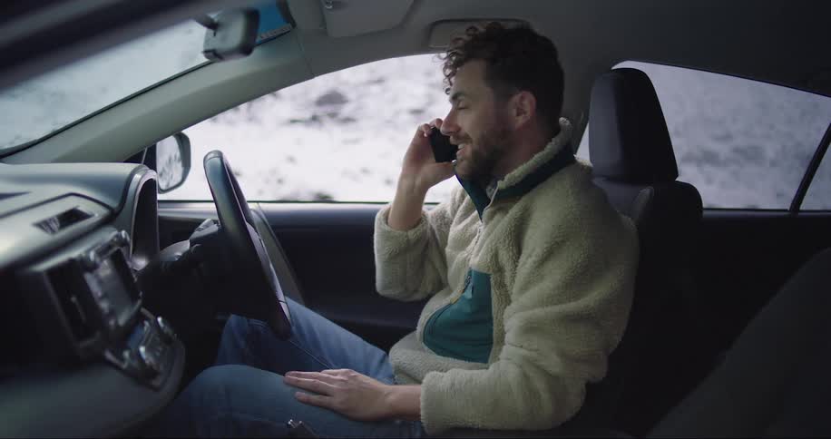 Man sitting in the car talking on the cellphone smiling