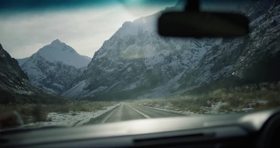 Vehicle on the road and around it mountains covered in snow