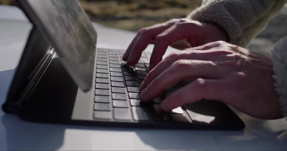 A man quickly types on the keyboard of a portable table computer