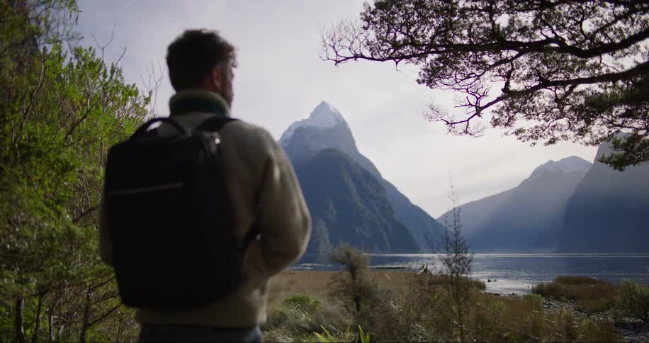 Man stand with a backpack facing mountains