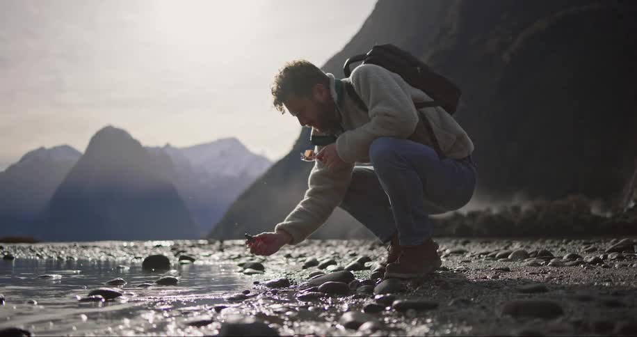 An explorer squatting by the river bank