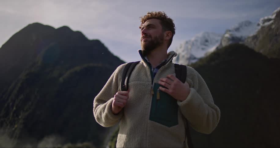 A hiker with a backpack standing in front of snowy mountains