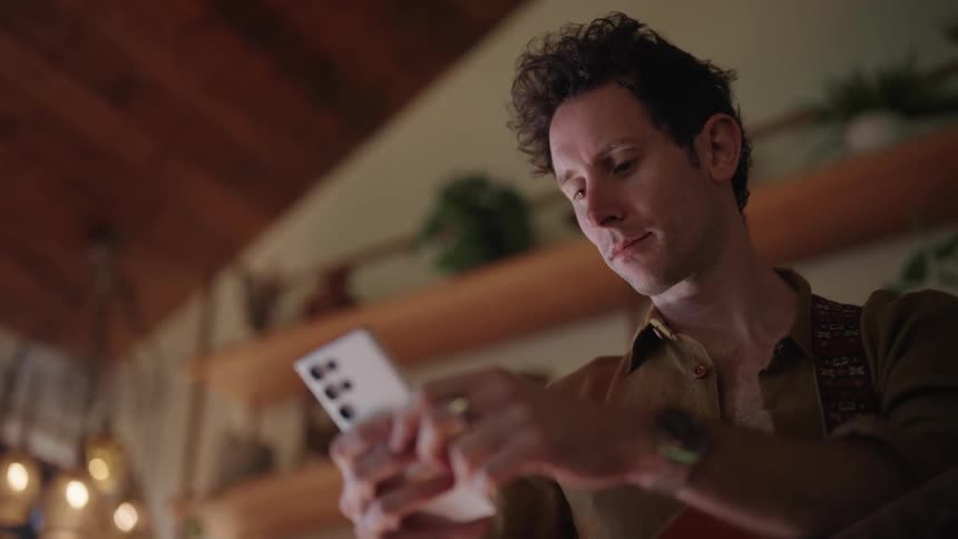 Young man texting on his phone in the living room