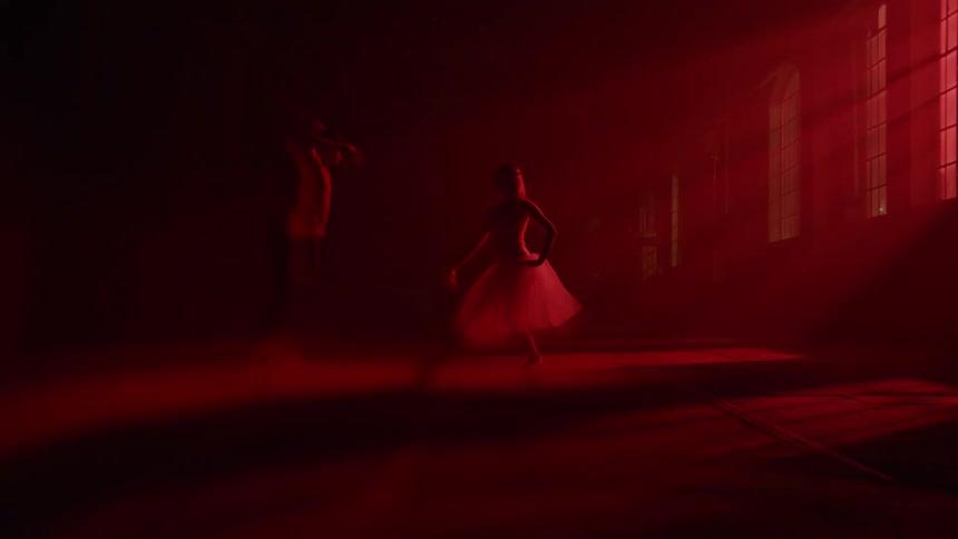 A couple of dancers dancing in a dark room with red light