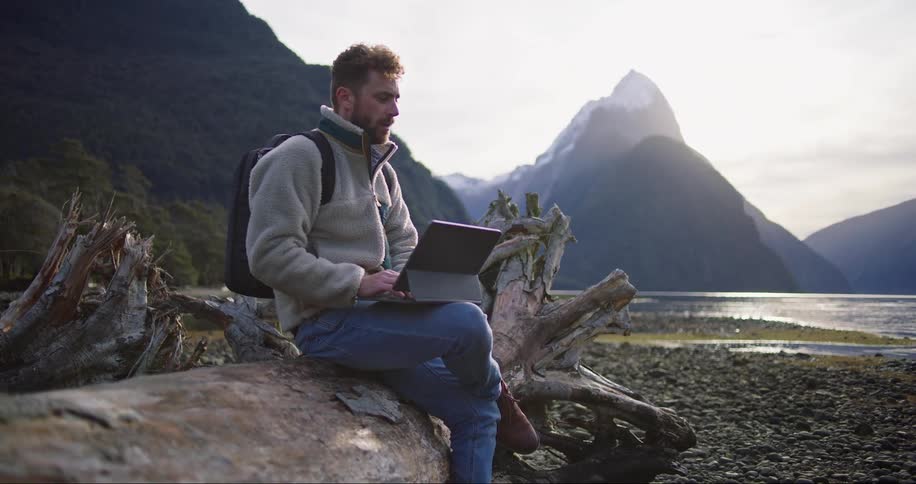 A man sitting and operating a tab on the woods