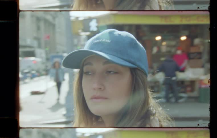 Closeup on the face of a young adult woman wearing a blue cap and walking