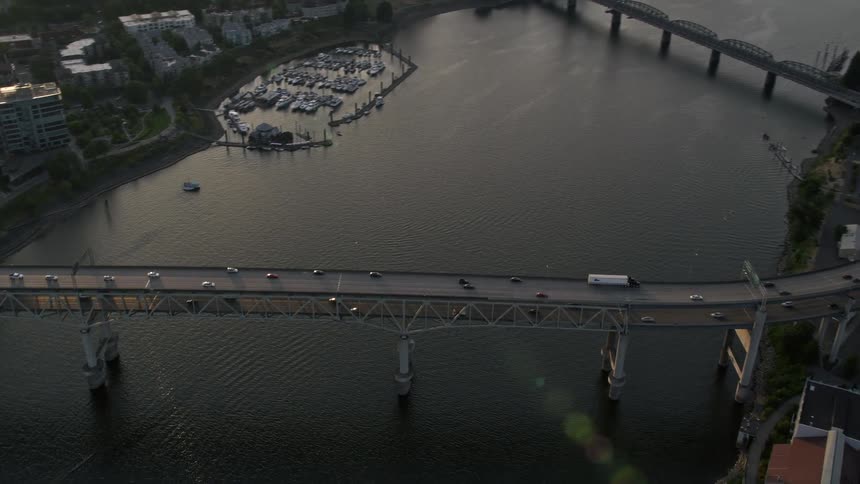 Aerial footage of Marquam Bridge passing over the Willamette River tilting up to reveal the downtown area of Portland Oregon during a beautiful sunset