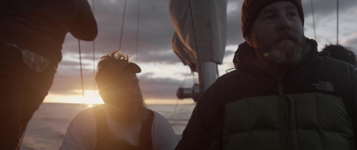 Two men are on a boat at sunset