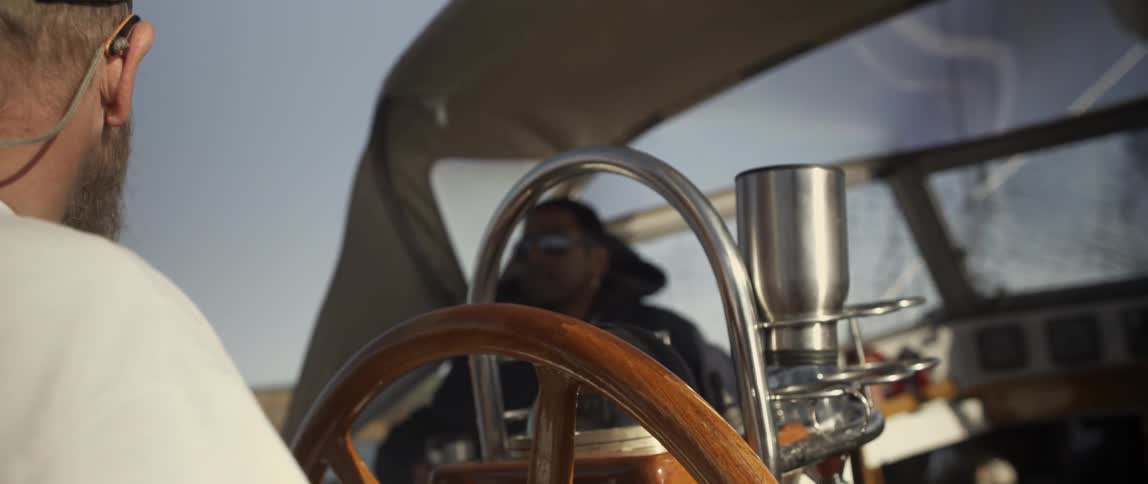 A man sits at the helm of a boat