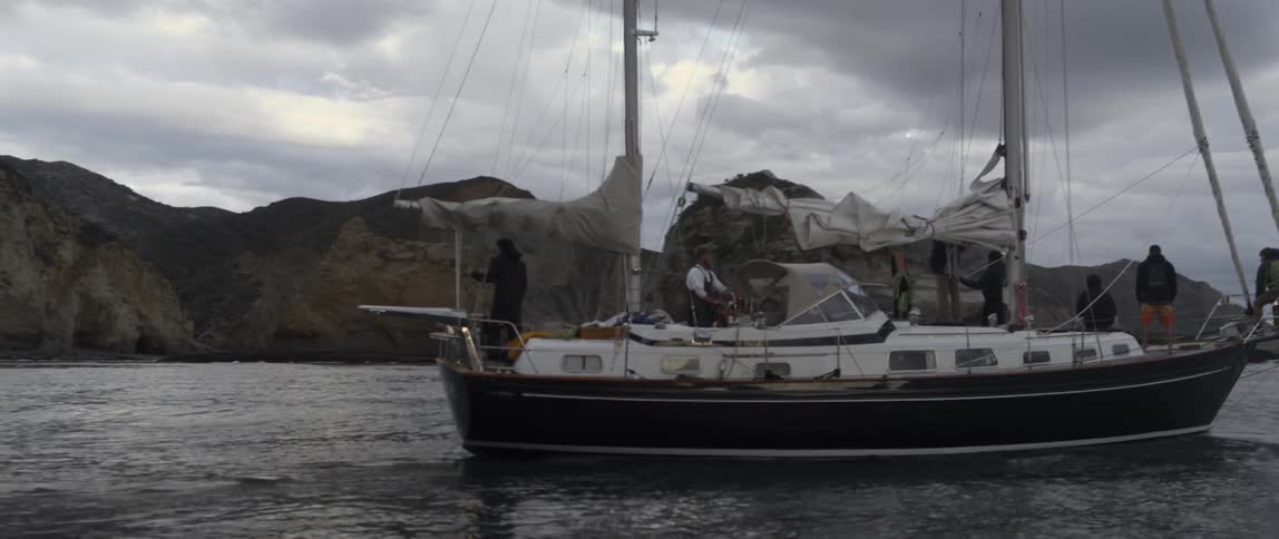 A boat is moving in the water with it's sails down