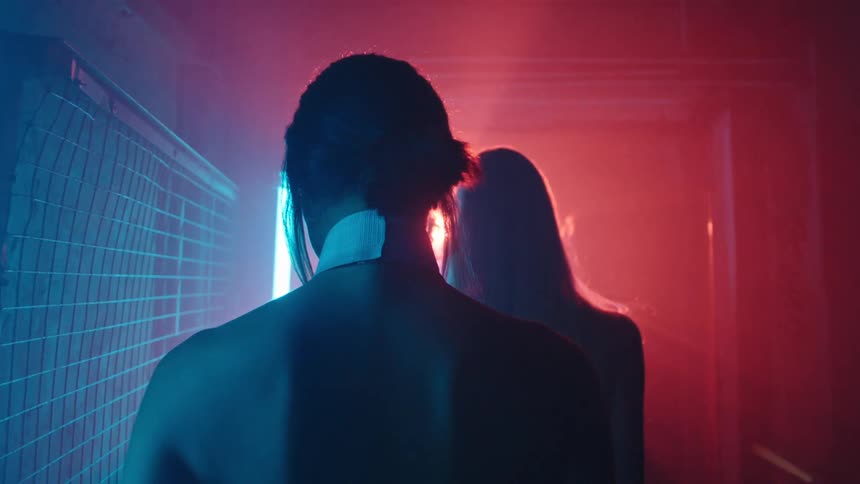 People walking in an indoor corridor with red and blue lights
