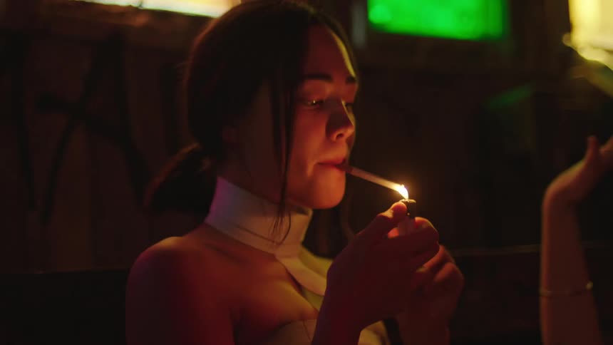 A young woman is lighting a cigarette in a nightclub setting