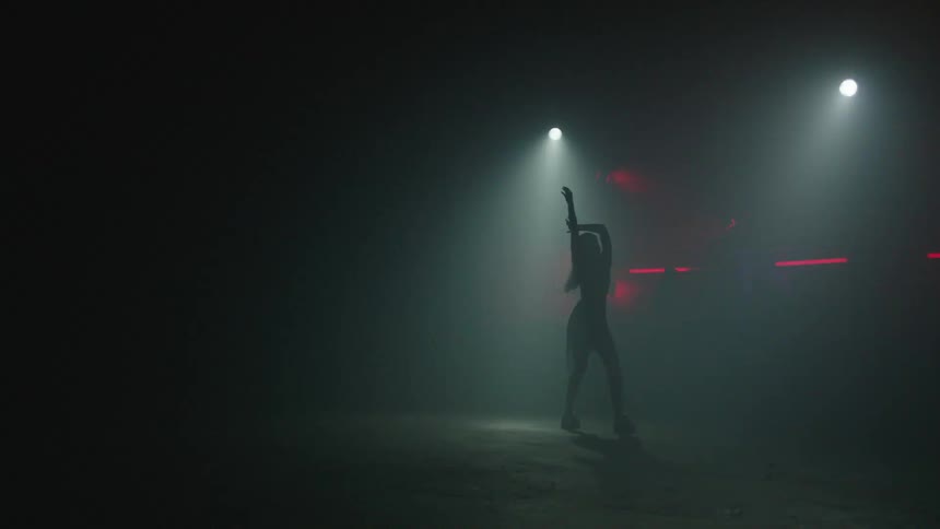 Silhouette of a woman dancing on stage under strobing lights