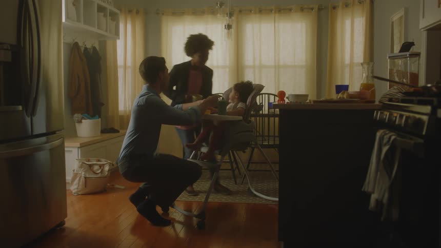 Father getting ready to feed his baby daughter and mother running and giving her baby a kiss