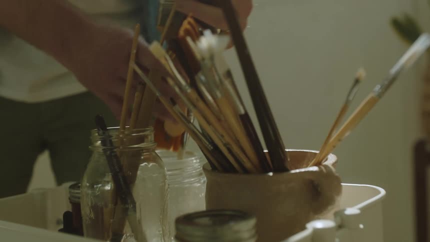 Male painter places paint brushes in containers