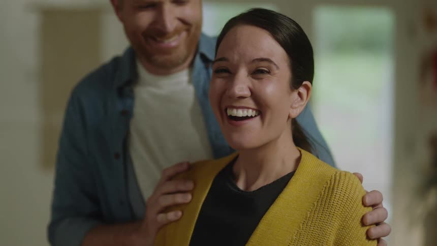 Man gives his wife a surprise and she smiles while hugging him