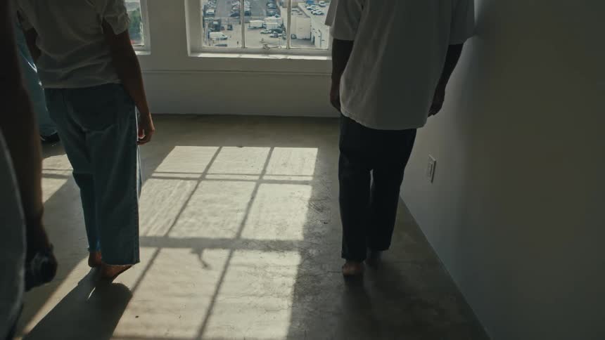 Time is frozen as a group of people stand motionless in the shadow of a window