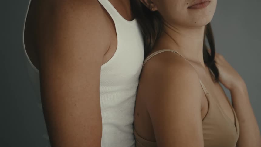 A man and a woman are embracing and the woman places her hand on her own shoulder