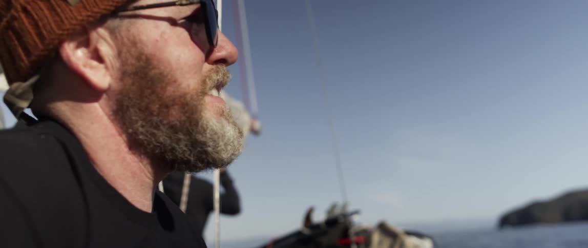 A man is talking as he looks out the side of a boat