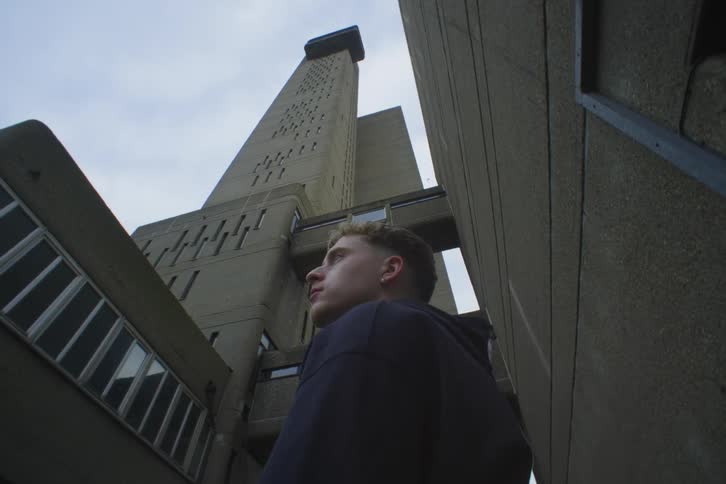 A male wearing a jacket standing near a high rise building