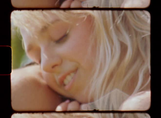 A man with beard hugging a blond woman with the soft wind blowing