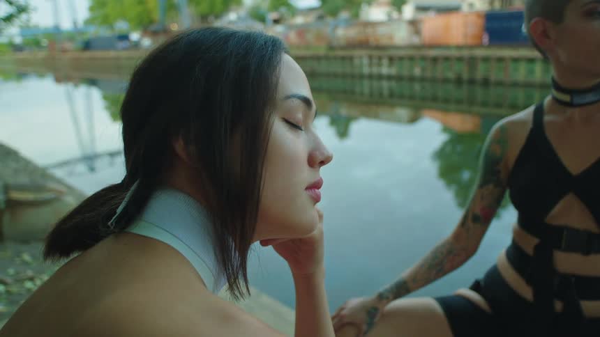 A woman with closed eyes pensive near a lake reflecting the city
