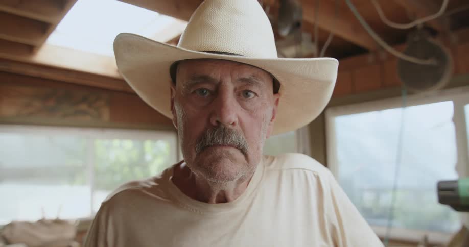 A hat wearing man in a workshop looking fearless