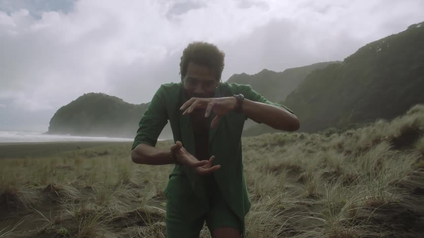 A man dancing in the grass on a beach on a cloudy day