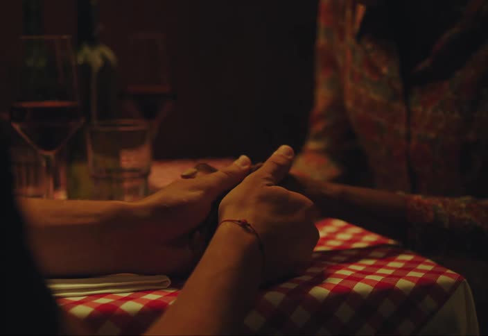 A woman on a dinner date laughs excitedly as a man slips a ring onto her finger and then hugs her