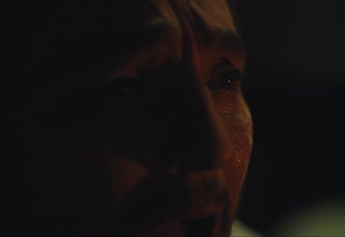 Man stares as he yells and cries outdoors at night