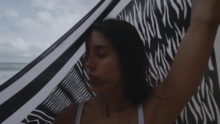 A woman lifts her towel on the beach