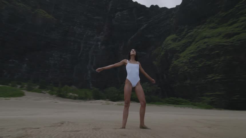 Lady swirling with her arms stretched near big rocks