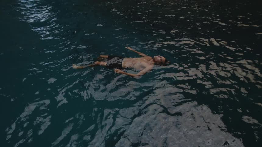 A man wearing short while swimming and floating in a river