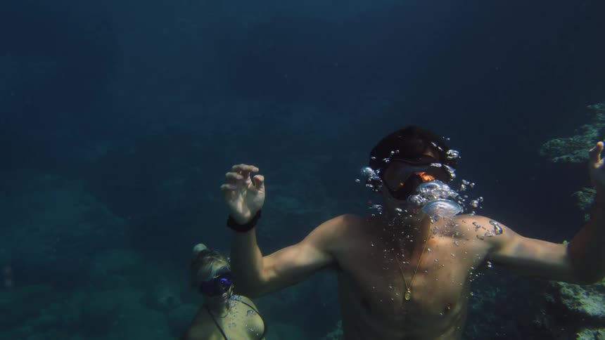 Two young people are diving to the bottom of the ocean