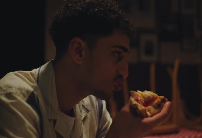 A man eats pizza with friends on a closed restaurant