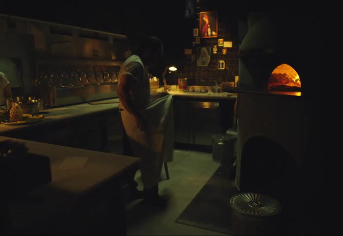A man observes the woodfired oven then takes off his apron sits in the chair and angrily throws the apron on the ground