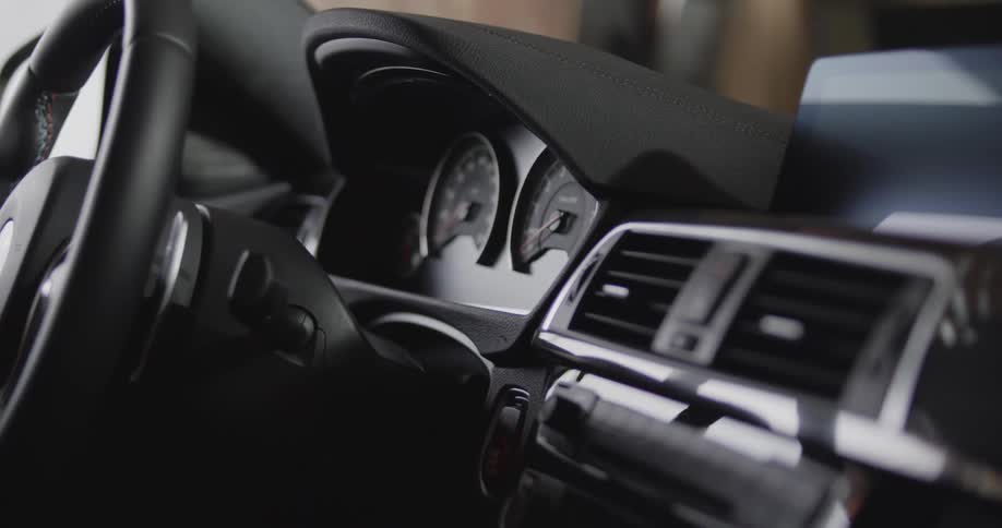 The dashboard steering wheel and front controls of a car are seen from inside the car