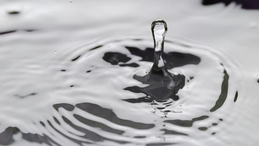 Slow motion of a water droplet falling and creating ripples and splashes