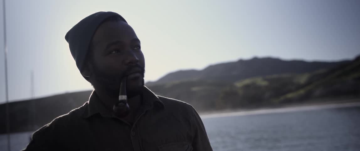 A man is listening to someone while smoking a pipe