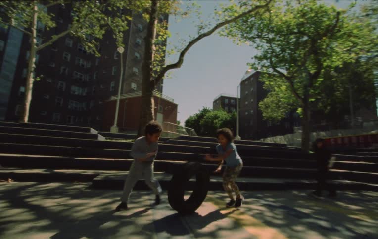 Kids play with a tire on a park in the city