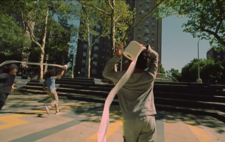 Three children holding a roll of toilet paper running and playing in a public place