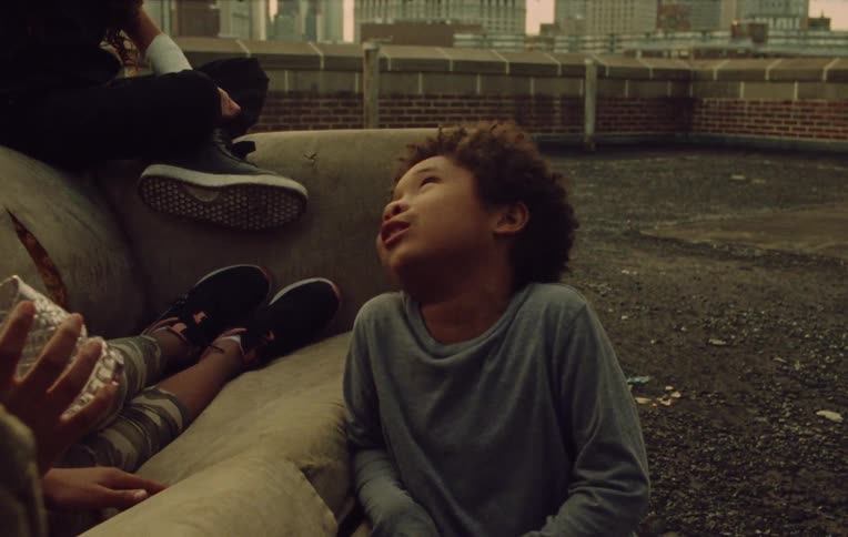 Children chat on a sofa on the roof of a building