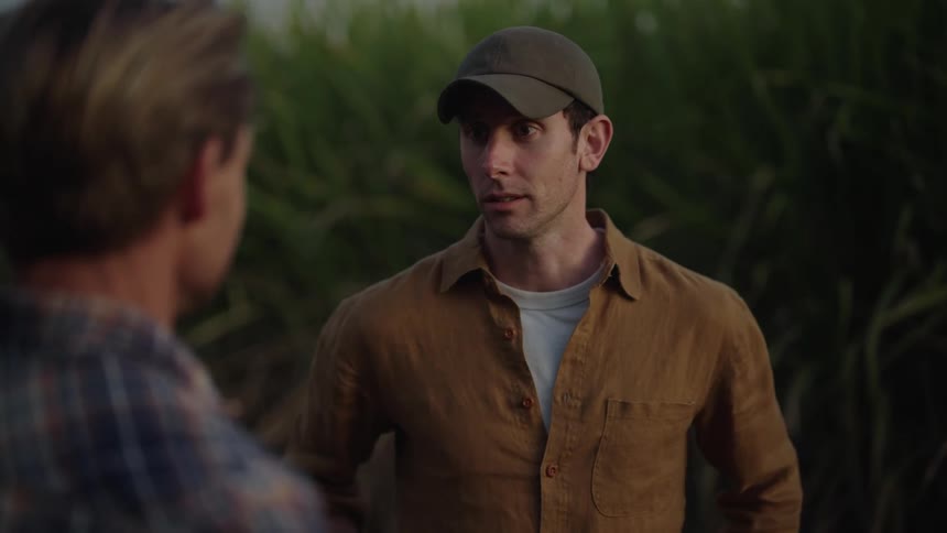 Man in a cap chats with another man outdoors
