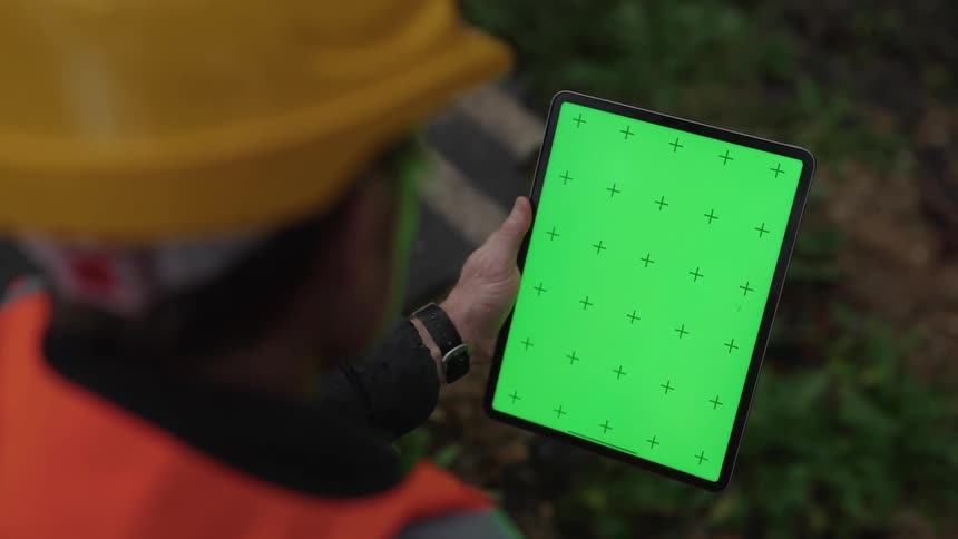 Worker wearing a hard hat holds a tablet with a green replaceable screen