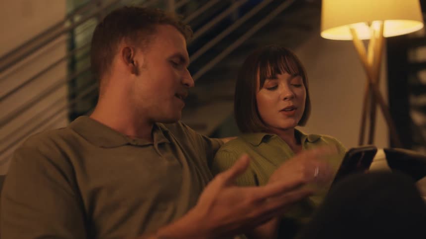 A couple is chatting while looking at something on their cell phone